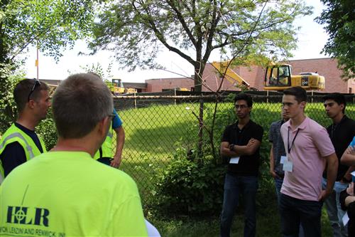 Student interns in front of construction equipment at a school 