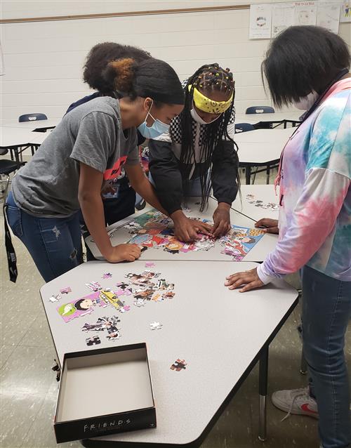 Students in LEAD work on a puzzle on a table together 