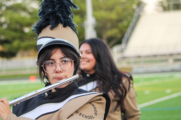  A girl with glasses plays the flute on a football field