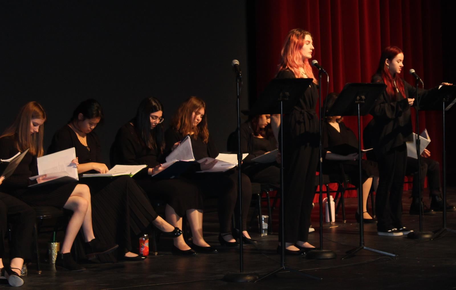  Students read from stands on a stage 