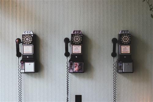 Three vintage telephones in a row on a wall.  