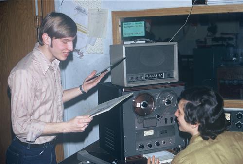 students at radio station holding a record 